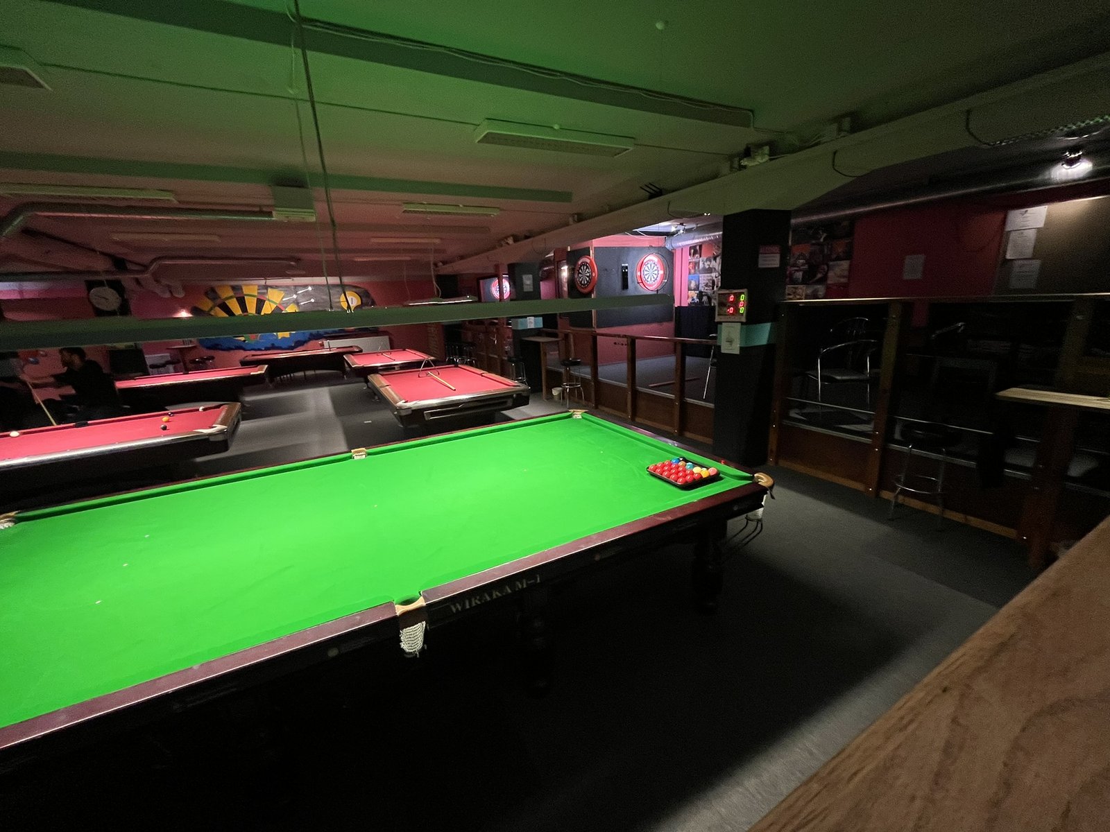 Snookerhallen med stora snookerbord, biljardbord och dart i bakgrunden.